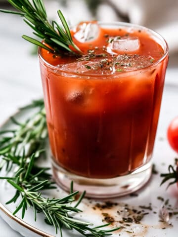 Bloody mary cocktail with rosemary and ice in a glass.