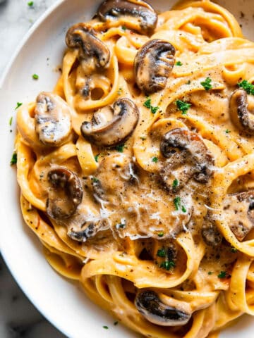 Creamy mushroom and pumpkin fettuccine in a bowl with herbs.