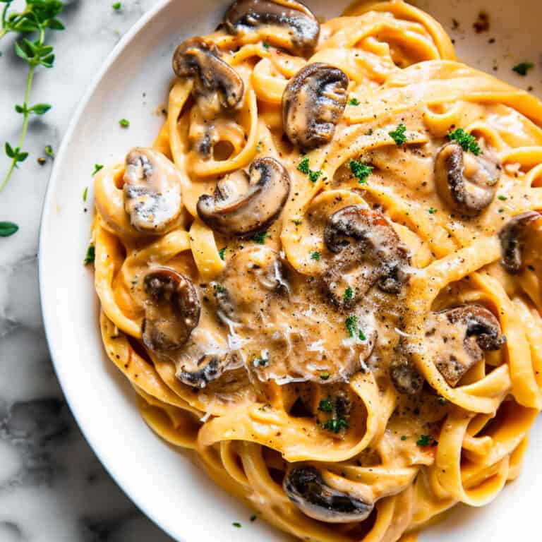 Creamy mushroom and pumpkin fettuccine in a bowl with herbs.