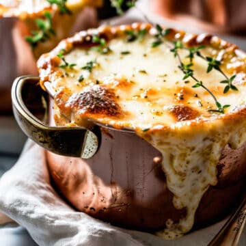 Easy french onion soup with melted cheese and fresh thyme leaves in soup bowls.