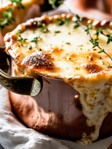Easy french onion soup with melted cheese and fresh thyme leaves in soup bowls.