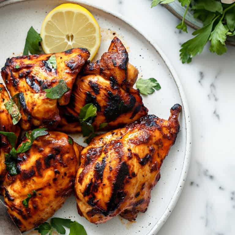 Grilled Moroccan chicken on a white plate.