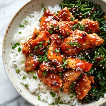 Sticky spicy Korean chicken with rice in a white bowl.