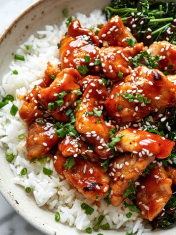 Sticky spicy Korean chicken with rice in a white bowl.