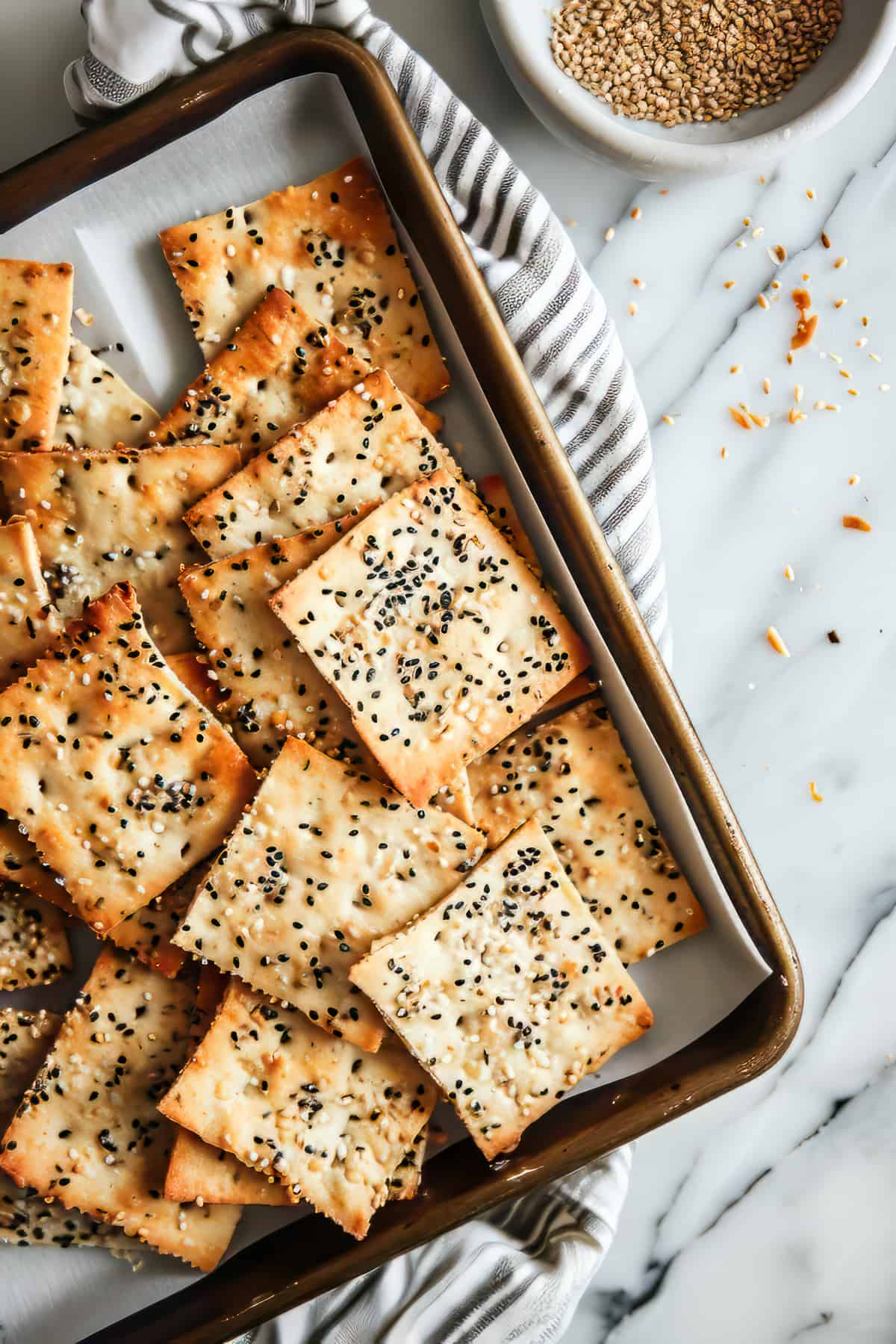 Homemade flatbread crackers with seeds on a baking tray.