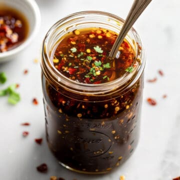 Homemade honey garlic sauce in a jar with a spoon.