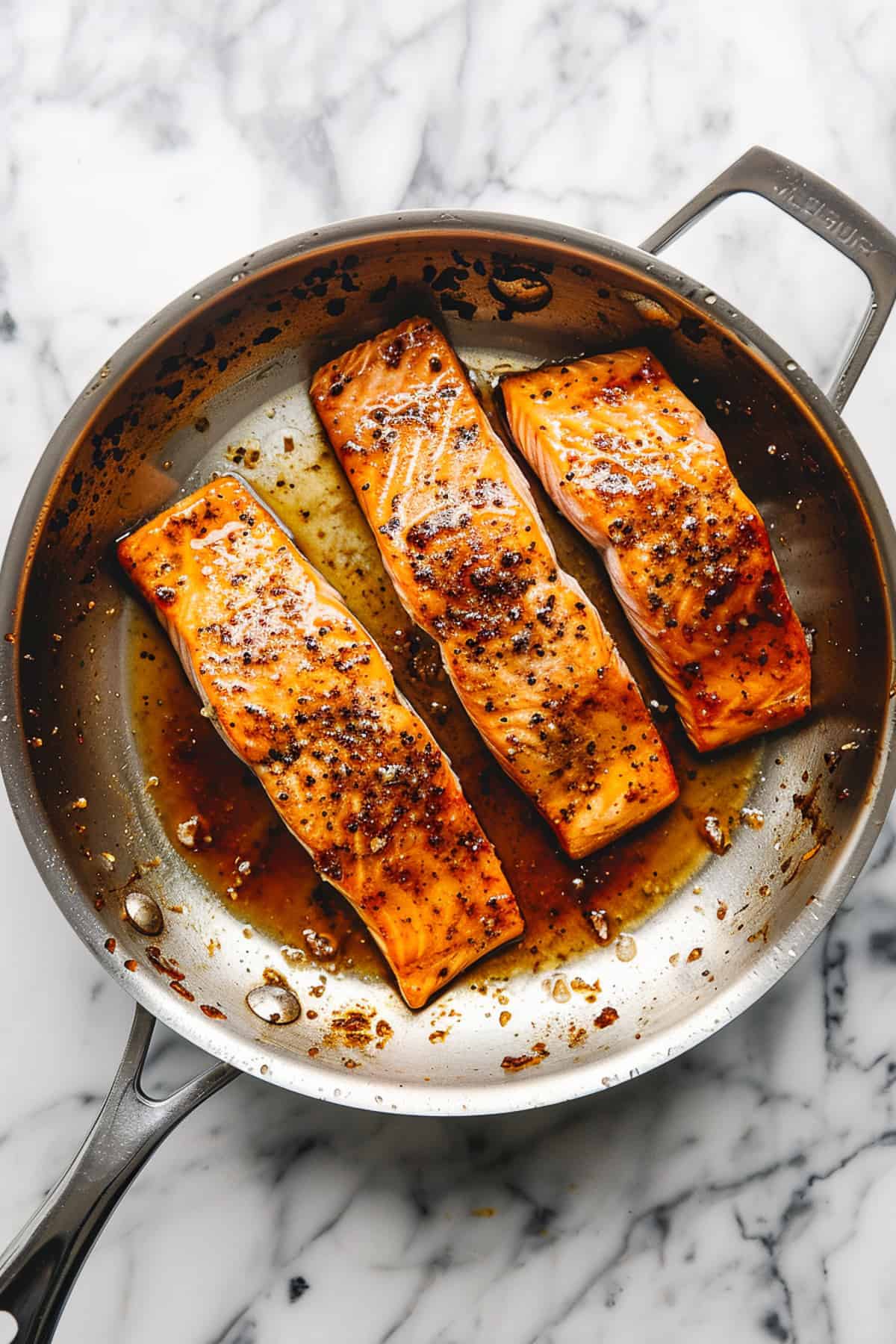 Maple glazed salmon in a pan with spices and sauce.