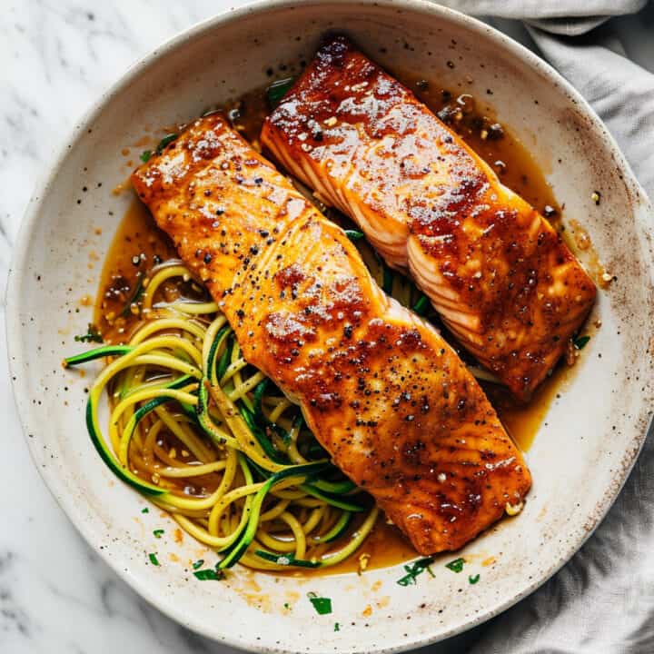 Maple glazed salmon in a pan with zucchini noodles.