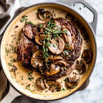 Pan-seared steak with cream mushroom sauce and herbs.
