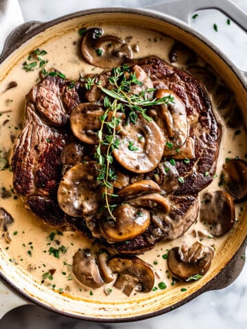 Pan-seared steak with cream mushroom sauce and herbs.
