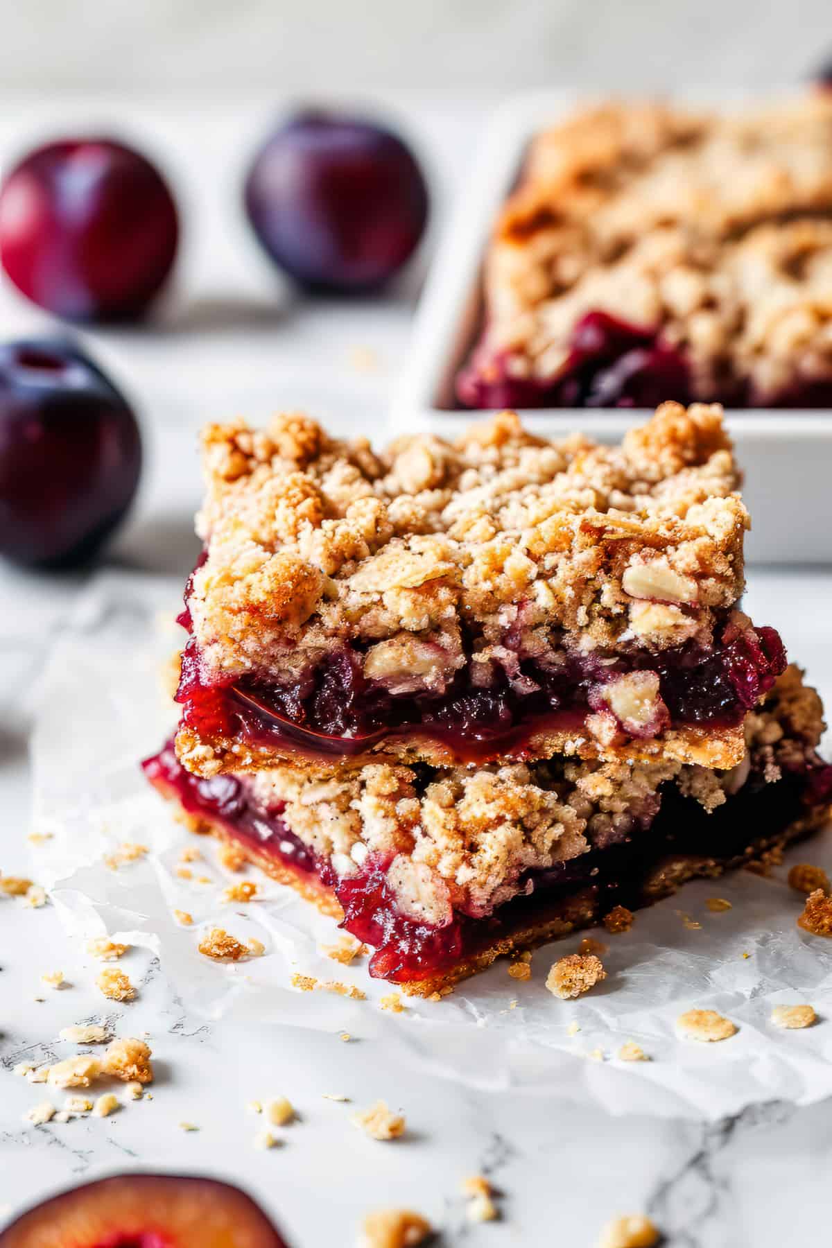 Plum bars with oat crumble on a piece of baking paper.