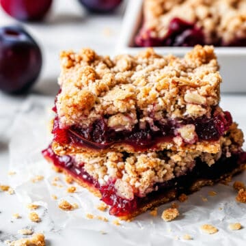 Plum bars with oat crumble on a piece of baking paper.