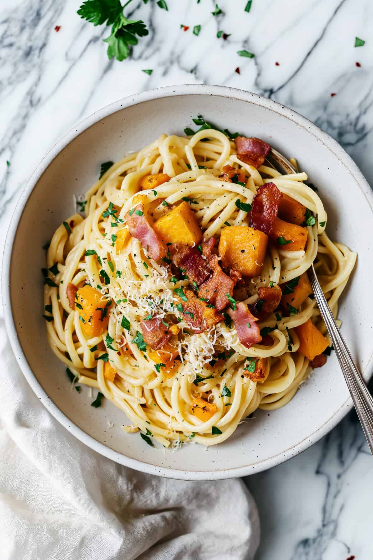 Pumpkin carbonara spaghetti with bacon and herbs.