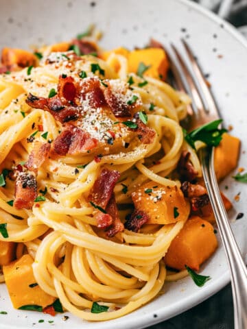 Pumpkin carbonara spaghetti with bacon and herbs.