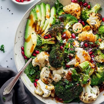 Warm roasted broccoli winter salad with vinaigrette dressing in a white bowl.