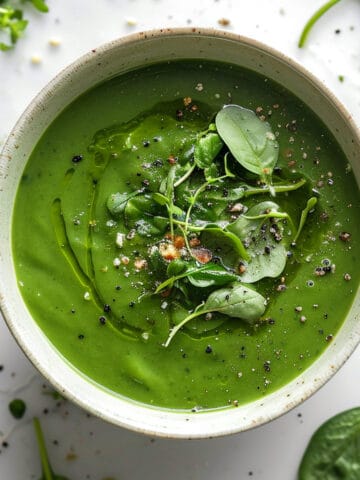 Watercress soup in a white bowl with pepper and olive oil.