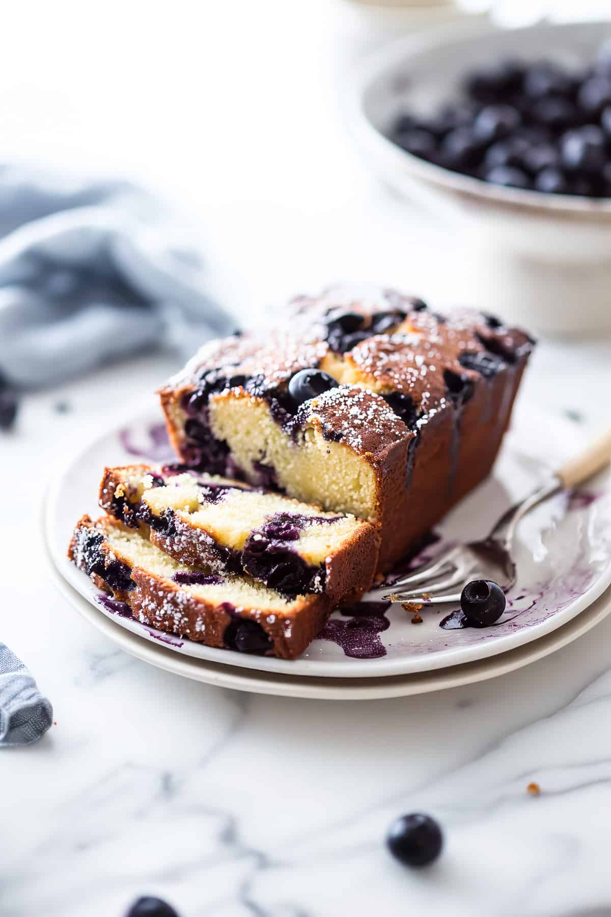 Soft and fluffy lemon blueberry loaf on a white plate.
