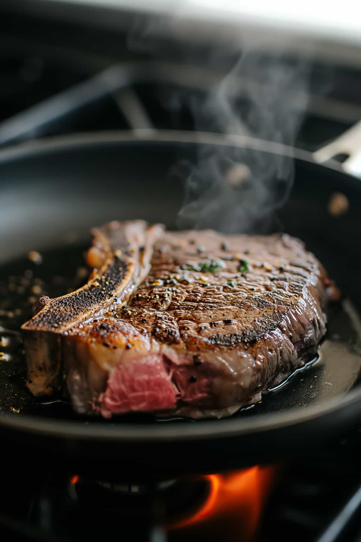 Rib eye steak in a pan being seared.