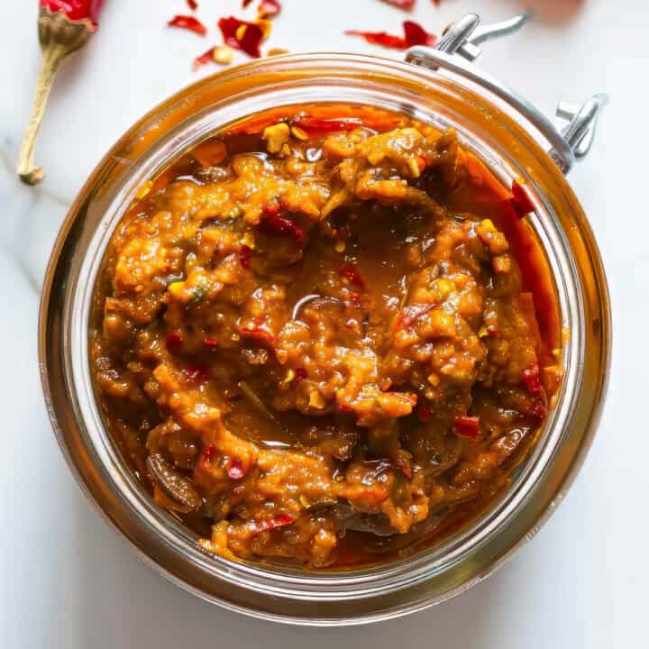 Homemade Thai red curry paste in a jar on a white table.