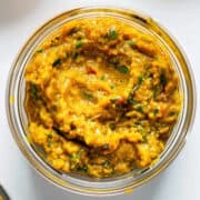 Homemade Thai yellow curry paste in a jar on a white table.