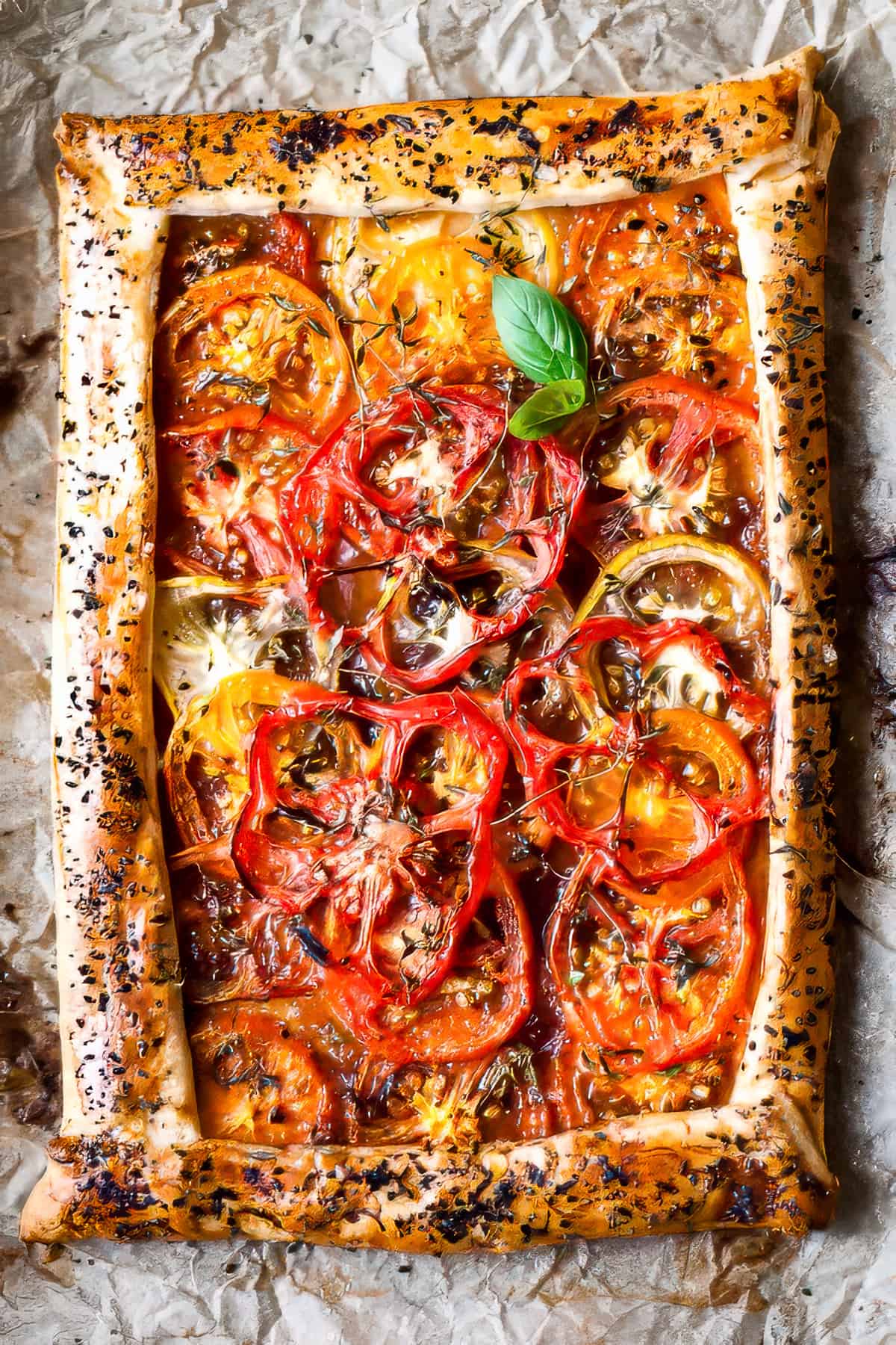 Baked tomato tart with thyme and basil on a baking tray.