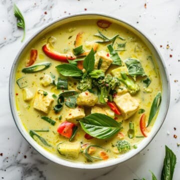 Vegetarian Thai green curry with tofu and herbs in a white bowl.