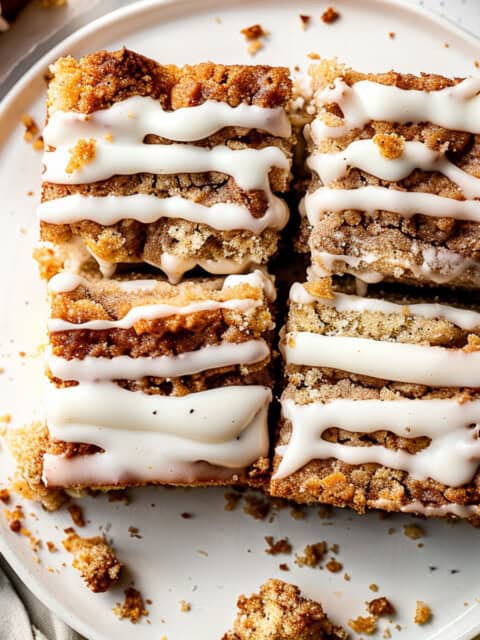 Apple coffee cake with cream cheese glaze on a white plate.