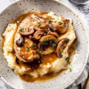 Crock pot pork chops over mashed potatoes with herbs and mushroom sauce.