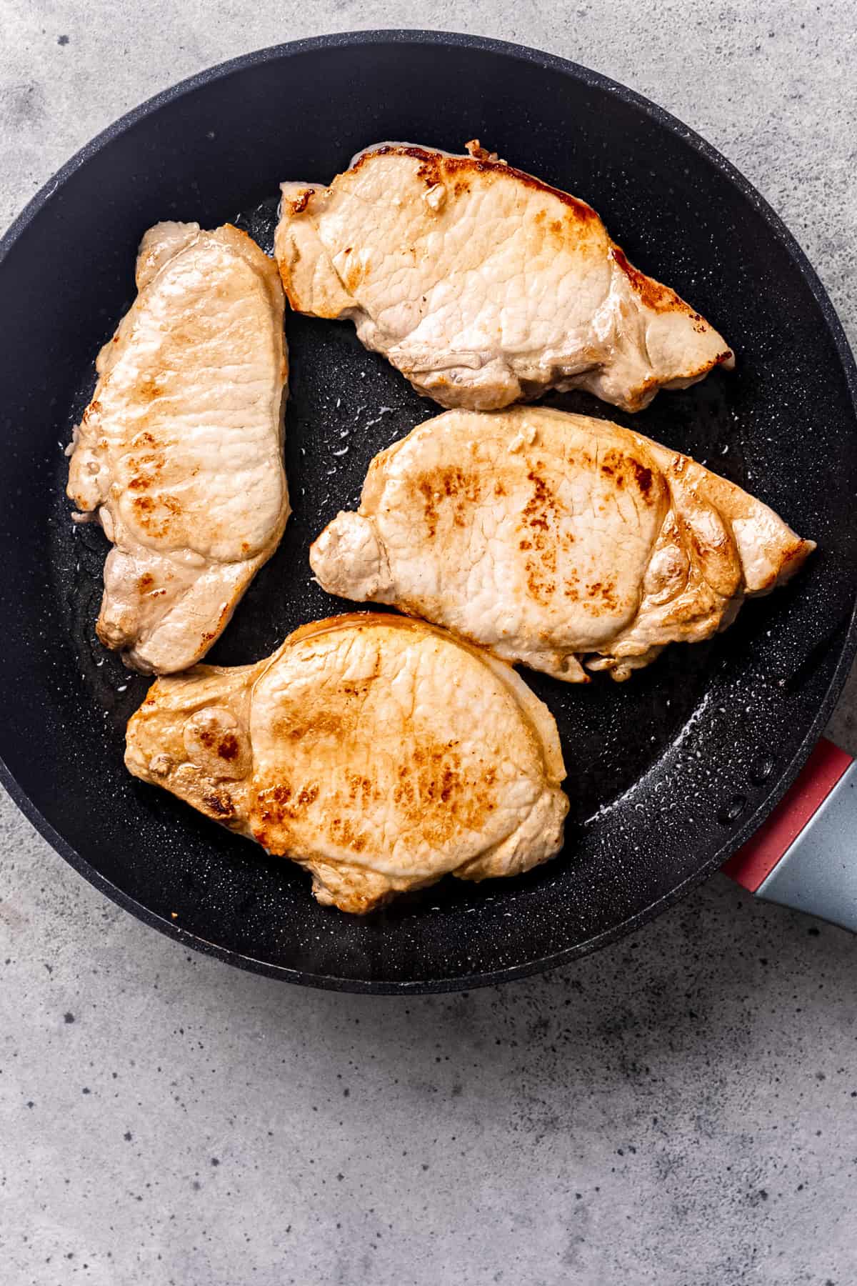 Searing pork chops in a pan.