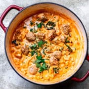 Italian sausage soup with cheese and spinach in a soup pot.