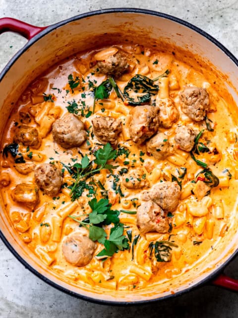 Italian sausage soup with cheese and spinach in a soup pot.