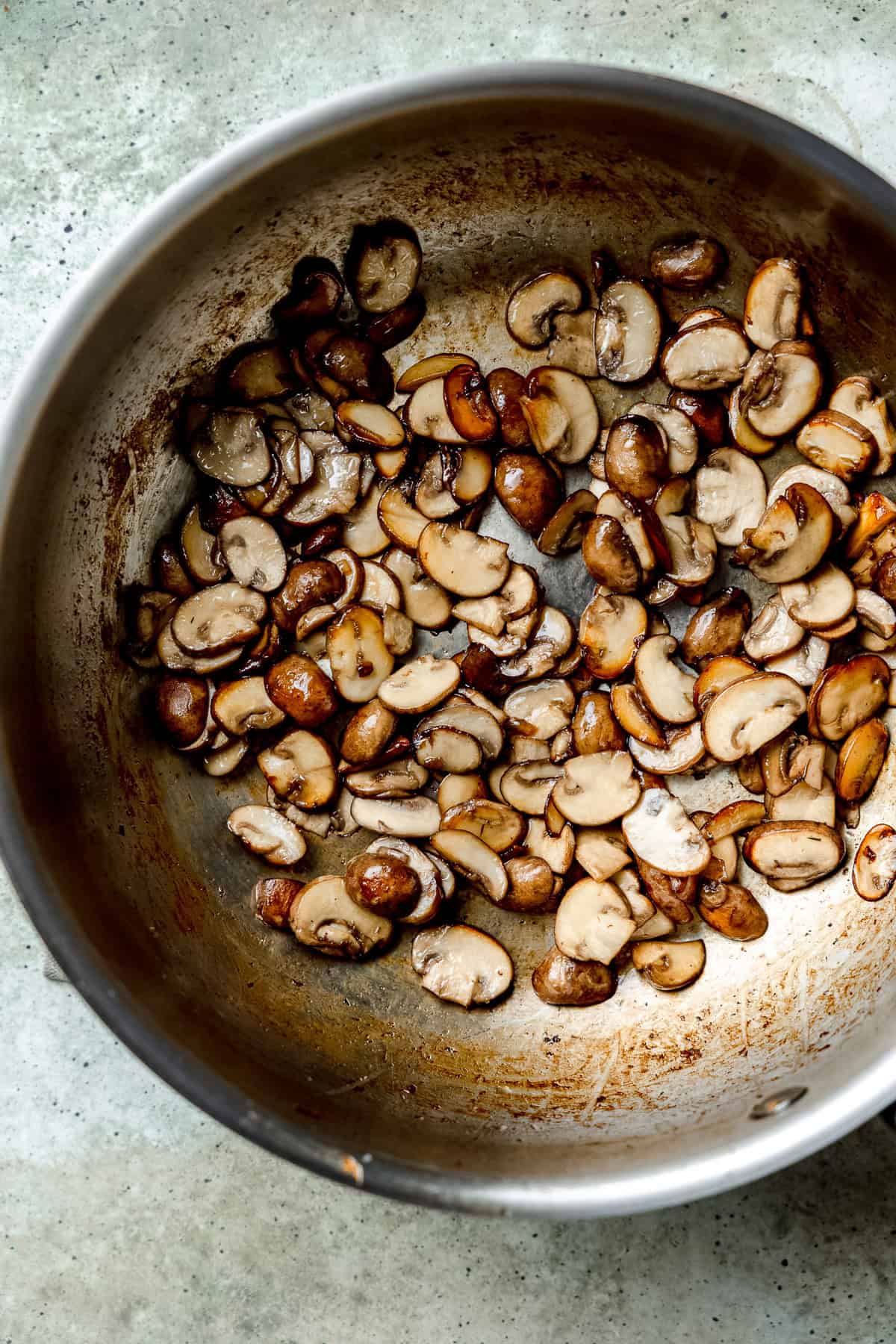Mushrooms being sautéed in a pan.