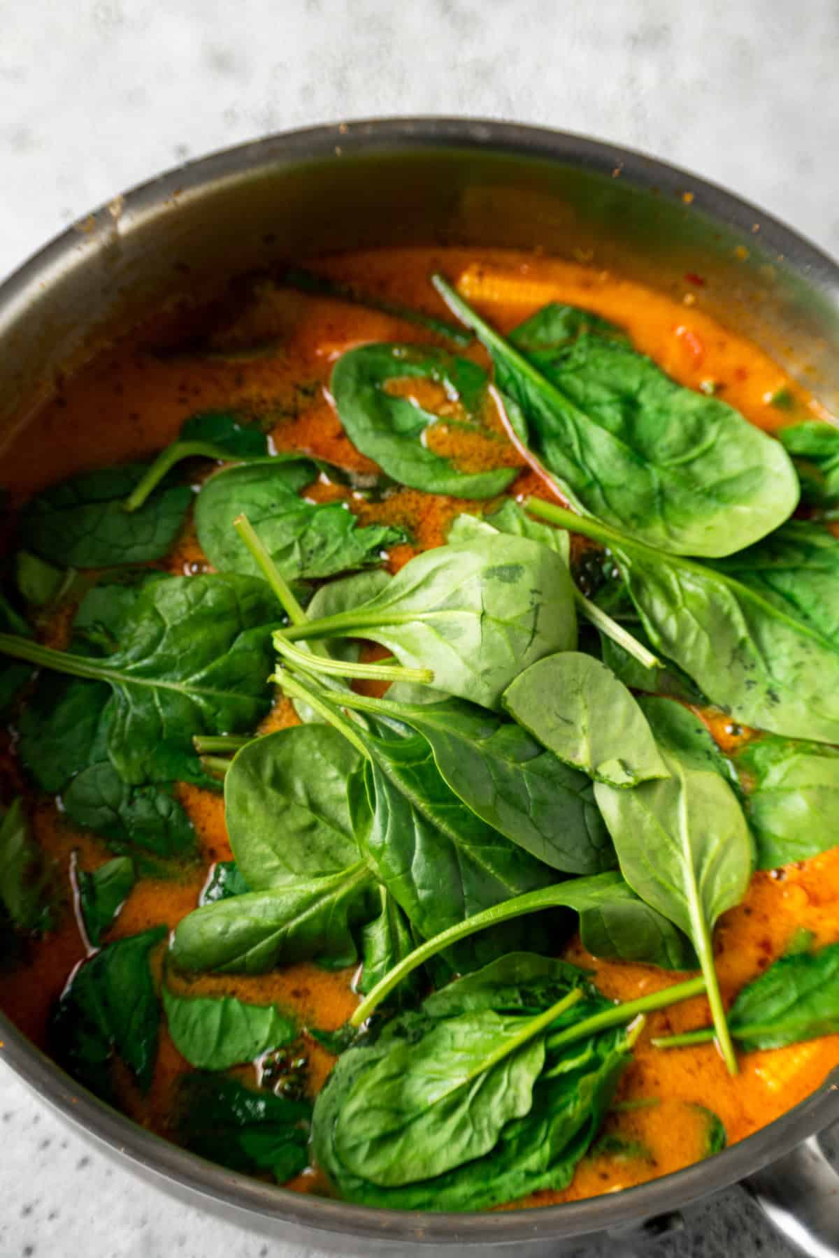 Spinach being added to Thai red curry.